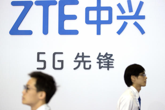 In this Sept. 26, 2018 file photo, visitors walk past a display from Chinese technology firm ZTE at the PT Expo in Beijing.