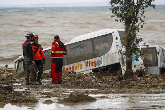 Rescuers stand next to a bus carried away after heavy rainfall triggered landslides that collapsed buildings and left as many as 12 people missing, in Casamicciola, on the southern Italian island of Ischia, Italy, on Saturday.