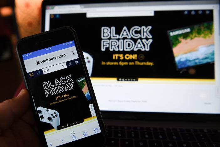 A picture taken in Liverpool, north west England on November 22, 2018 shows Black Friday sales branding on shopping websites displayed on smartphone and laptop screens.