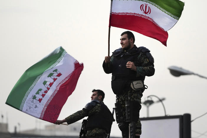 Two anti-riot police officers wave the Iranian flags during a street celebration after Iran defeated Wales in Qatar's World Cup, at Sadeghieh Sq. in Tehran, Iran, Friday, Nov. 25, 2022.