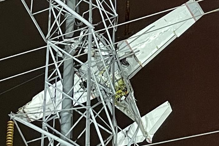 The small plane, pictured, can be seen trapped among the power lines as passengers remain stranded roughly 100 feet in the air.