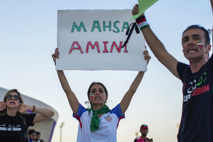 A woman at a protest in Qatar holds up a sign bearing the name of Mahsa Amini, the 22-year-old Iranian woman whose death in police custody sparked a nationwide protest movement.