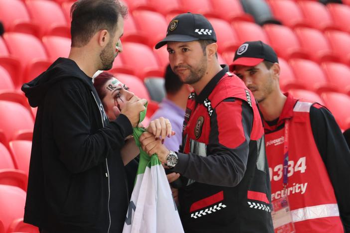 Members of security, right, speak with two Iran supporters as they take away a flag reading "Woman life freedom" prior to the match between Wales and Iran on Nov. 25.