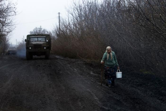 A woman carrying a bucket walks along the road near Bakhmut, on Nov. 27. As temperatures drop, Ukrainians worked to restore power, heat and water supplies after Russian strikes hit key infrastructure.