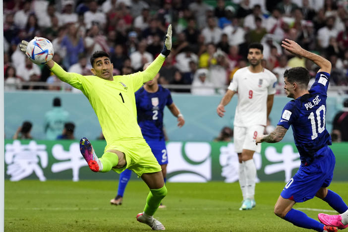 Christian Pulisic of the United States (right) shoots to score his side's first goal past Iran's goalkeeper Alireza Beiranvand during their teams' World Cup match.