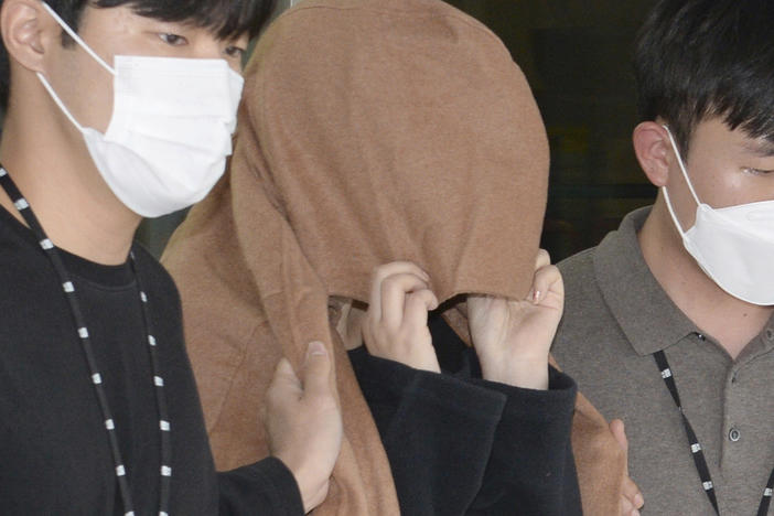 A woman, center, leaves to the Seoul Central District Prosecutors' Office at Ulsan Jungbu police station in Ulsan, South Korea, on Sept. 15, 2022.