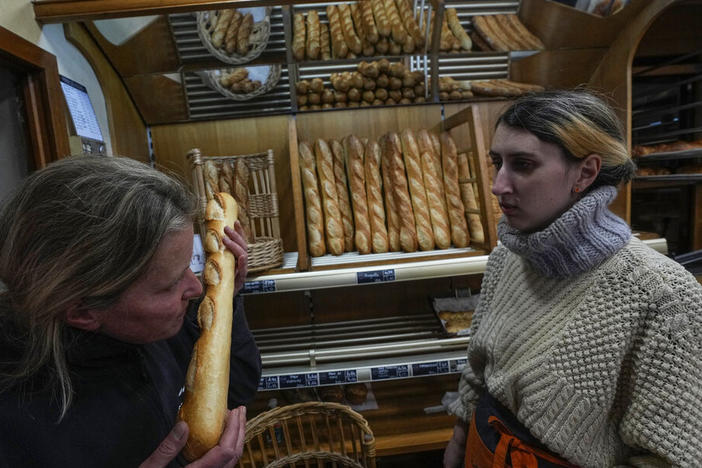 Bakery owner Florence Poirier smells a baguette fresh from the oven Thursday as Mylene Poirier stands next to her at a bakery, in Versailles, west of Paris.