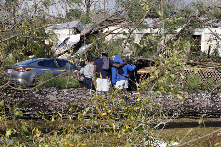 Friends and family pray outside a damaged mobile home on Wednesday in Flatwood, Ala., the day after a severe storm swept through the area. Two people were killed in the Flatwood community just north of the city of Montgomery.