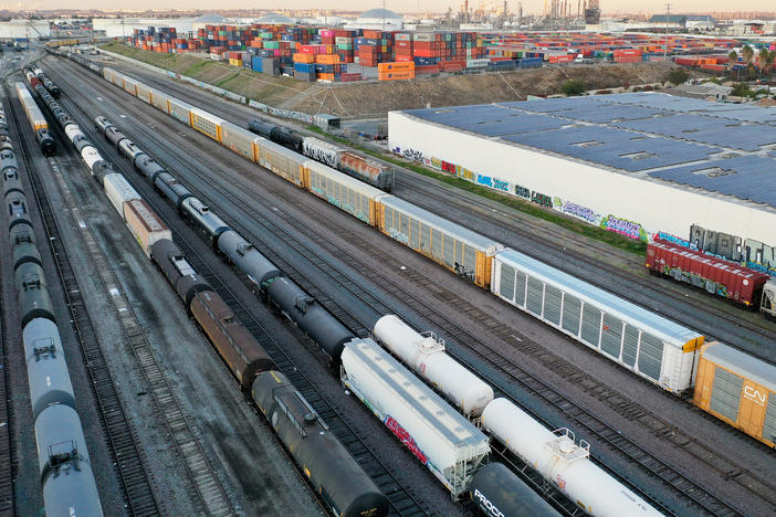 In an aerial view, freight rail cars sit in a rail yard near shipping containers on Nov. 22 in Wilmington, Calif.