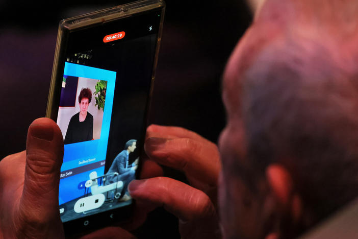 An attendee makes a video as FTX founder Sam Bankman-Fried speaks during the New York Times DealBook Summit in the Appel Room at the Jazz At Lincoln Center on November 30, 2022 in New York City.