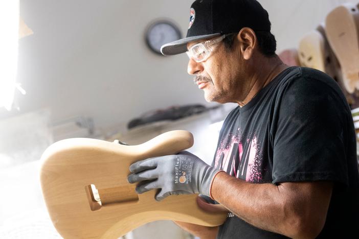 A builder sands the body of a guitar at the Fender factory, in Corona, California, on October 6, 2022. Industries sensitive to rising interest rates have been slowing hiring.