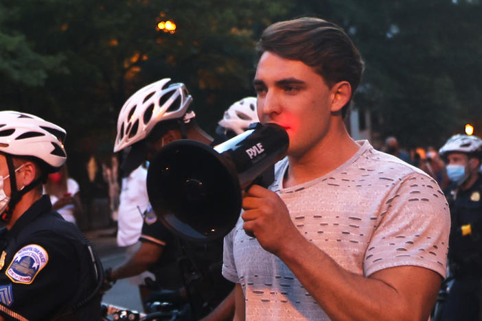 Jacob Wohl, pictured here surrounded by police officers at a 2020 protest in Washington D.C., is one of two right-wing activists who were behind a 2020 robocall scheme that targeted minority voters. Wohl will now face probation, fines and 500 hours of voter registration assistance for pleading guilty to telecommunications fraud.