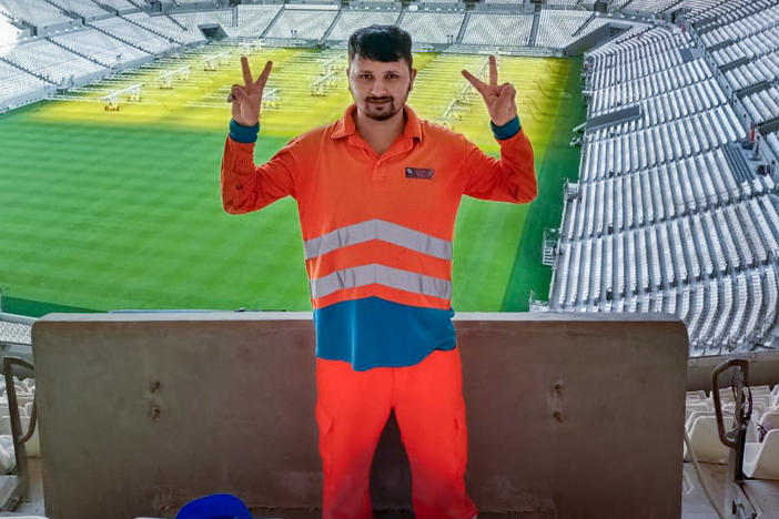 Anish Adhikari, now 26, worked construction jobs in Qatar for 33 months in the lead-up to the World Cup. In this 2021 photo, he poses inside the new Lusail stadium, which he helped build and which will host the World Cup final on Dec. 18. Adhikari says the Nepali agent who got him the job misled him about working conditions in Qatar: "They sell a dream that's not reality."