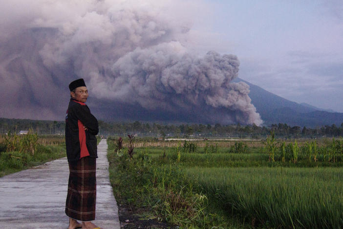 A man looks on as Mount Semeru releases volcanic materials during an eruption on Sunday, Dec. 4, 2022 in Lumajang, East java, Indonesia. Indonesia's highest volcano on the country's most densely populated island of Java erupted Sunday.