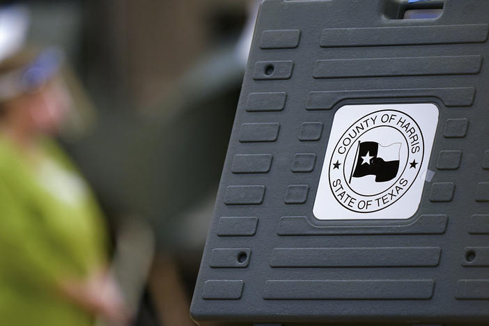 In this 2020 file photo, an election poll worker stands among voting machines in Houston. Texas state Republican leaders are accusing officials in Houston's Harris County of "election improprieties" that marred Election Day last month.