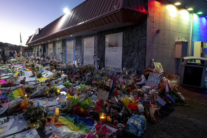 Mourners gather outside Club Q to visit a memorial, which has been moved from a sidewalk outside of police tape that was surrounding the club, on Friday, Nov. 25, 2022, in Colorado Spring, Colo.