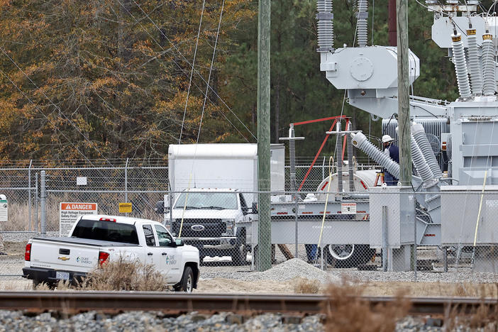 Workers work on equipment Monday at a power substation in West End, N.C., where an attack on critical infrastructure caused a power outage.