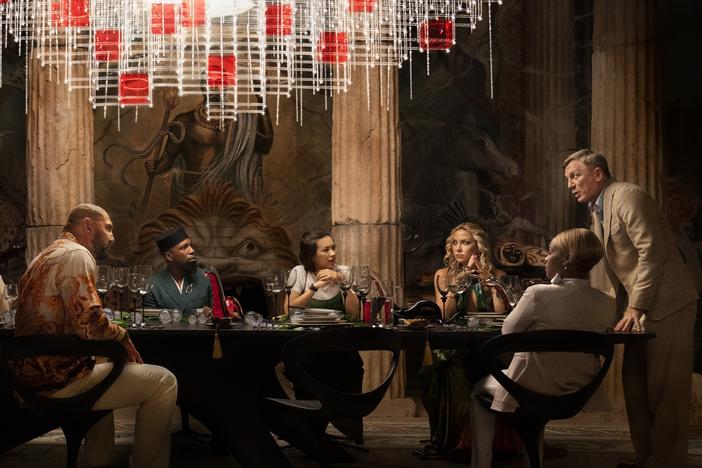 Edward Norton (left) plays a tech billionaire who hosts a murder mystery party for an assortment of guests (Madelyn Cline, Kathryn Hahn, Dave Bautista, Leslie Odom Jr., Jessica Henwick, Kate Hudson, Janelle Monáe and Daniel Craig) in <em>Glass Onion. </em>
