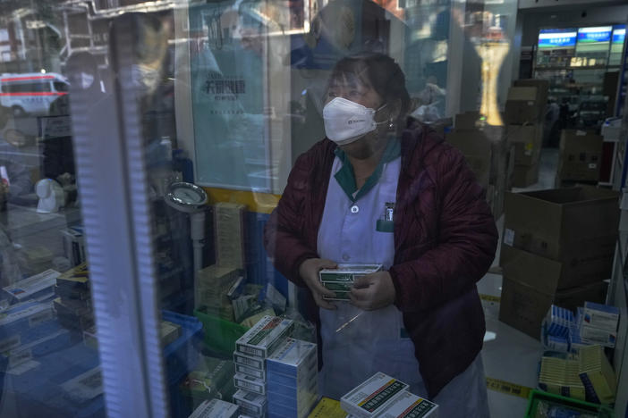 Residents are reflected on a door panel as they wait in line to buy medicine at a pharmacy in Beijing on Tuesday.