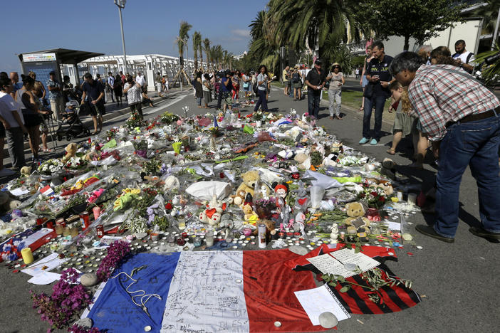 People look at flowers placed on the Promenade des Anglais at the scene of a truck attack on July 18, 2016, in Nice, southern France. A French court on Tuesday convicted eight people charged in connection with the Bastille Day attack that killed 86 people.