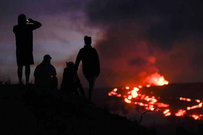 People watch lava from the Mauna Loa volcano on Dec. 1. U.S. scientists declared Tuesday that two active Hawaii volcanoes — one where lava destroyed hundreds of homes in 2018 and another where lava recently stalled before reaching a crucial Big Island highway — have stopped erupting.
