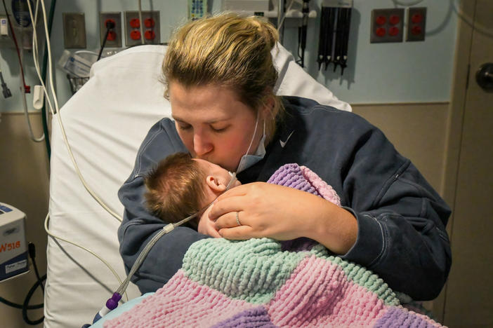 Caitlyn Houston kisses her seven-week-old daughter, Parker, as they wait in the ER for a hospital bed to open up on Dec. 7 at Corewell Health Helen DeVos Children's Hospital in Grand Rapids, Michigan. "There's so many kids in here that they have to take the ones that are really bad," Houston said.