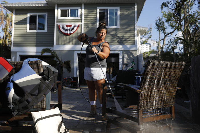 Susan Elliott power washes her outdoor furniture at her home in Fort Myers Beach, Fla., where a powerful storm surge from Hurricane Ian ravaged the community.