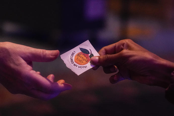 A poll worker hands off a Georgia Voted sticker to a voter on Election Day, Nov. 8, in Atlanta.