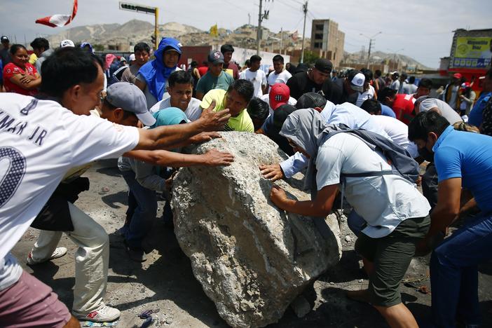 Supporters of ousted Peruvian President Pedro Castillo work together to roll a boulder onto the Pan-American North Highway during a protest against his detention, in Chao, Peru, on Thursday.