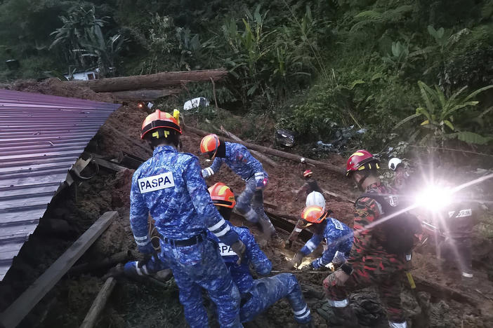 In this photo provided by Civil Defense Department, Civil Defense personnel search for survivors buried after a landslide hit a campsite in Batang Kali, Malaysia, on Friday.