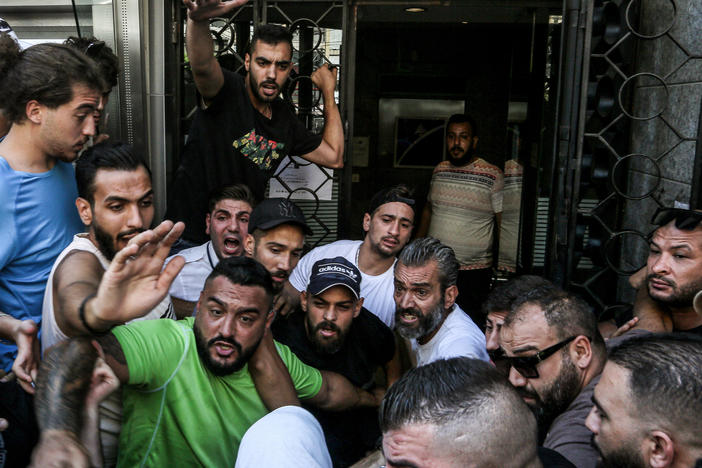 Lebanese activists gather outside a local bank in support of Abed Soubra, who stormed the branch demanding access to his own accounts, in Beirut on Sept 16. Lebanese police detained Soubra after he entered the bank and, armed with a gun, demanded access to his deposits. It was the third such incident in Lebanon that week alone.