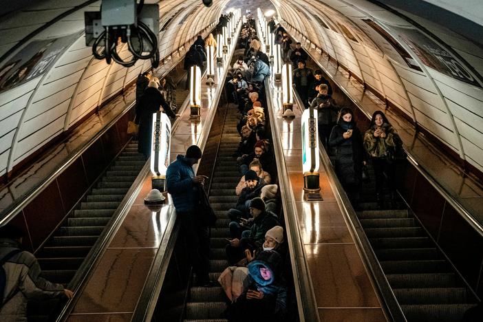 Civilians sit on an escalator while taking shelter inside a metro station during an air raid alert in the center of Kyiv on Dec. 16, 2022. A fresh barrage of Russian strikes hit cities across Ukraine early on Friday.