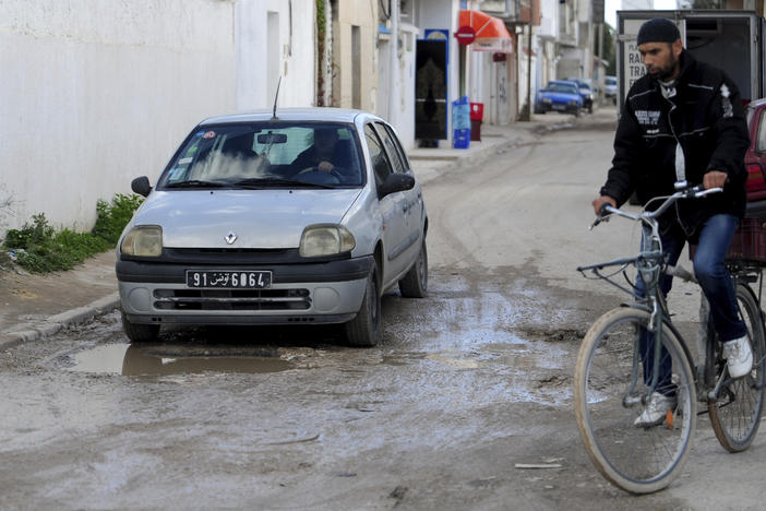 A man drives a car in a damaged street of La Marsa, outside Tunis, Wednesday, Dec. 14, 2022. To outsiders, Tunisia's legislative elections Saturday, Dec. 17, 2022 look questionable: Many opposition parties are boycotting. A new electoral law makes it harder for women to compete. Foreign media aren't allowed to talk to candidates.