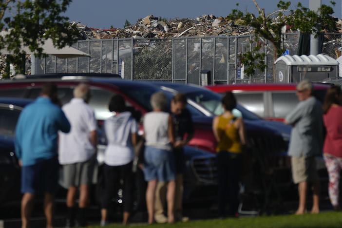 A pile of debris from Hurricane Ian rises behind a line of people waiting to vote in Fort Myers, Fla., in November 2022. Research suggests support for some climate policies increases immediately after climate-driven disasters such as Ian.