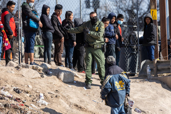 A U.S. Border Patrol agent instructs immigrants who had crossed the Rio Grande into El Paso, Texas on Dec. 19, as seen from Ciudad Juarez, Mexico. Over the weekend, El Paso declared a state of emergency, one week after a surge of asylum seekers began crossing the border, quickly overwhelming federal immigration and city authorities.