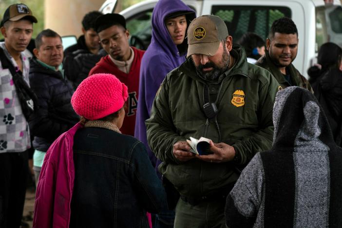 A Border Patrol agent checks an asylum-seeker's passport after she turned herself in, in Eagle Pass, Texas, on Dec. 19.