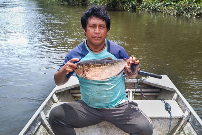 Takakudjyti Kayapó, better known as Takakre, holds up a <em>matrinxã</em> fish. A community fishing monitor, he will measure and weigh the fish before recording its details in a spreadsheet to be sent to other members of the team studying how the mercury used in illegal mining is affecting fish populations in the Pixaxá River.