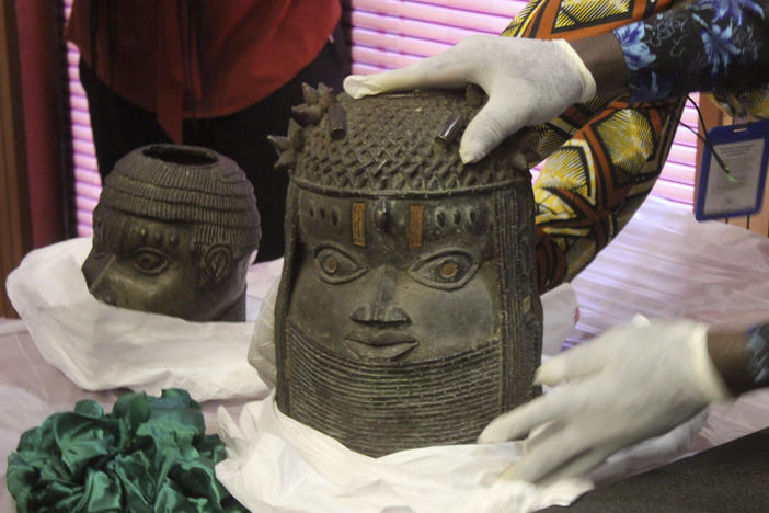 Looted Benin Bronzes that were returned by Germany to Nigeria are examined during a ceremony in Abuja on Tuesday. Nigerian officials said that more than 5,000 ancient artifacts are estimated to have been stolen from Nigeria, the majority by British colonizers.