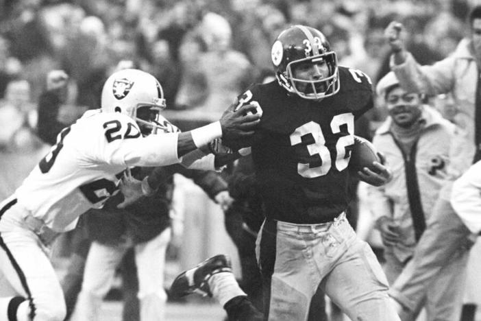 Pittsburgh Steelers' Franco Harris (32) eludes a tackle by Oakland Raiders' Jimmy Warren as he runs 42-yards for a touchdown after catching a deflected pass during an AFC Divisional NFL football playoff game in Pittsburgh in 1972. Harris died on Wednesday morning at age 72.