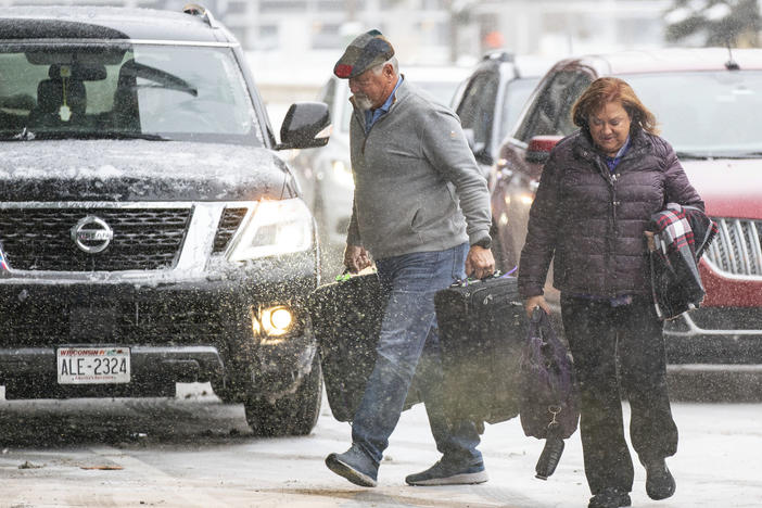 Travelers walk through the snow into Terminal 1 Wednesday, Dec. 21, 2022 at the Minneapolis-Saint Paul International Airport in Minneapolis.