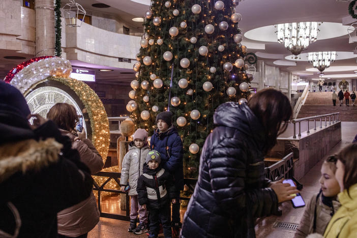 Children pose for photos in front of a Christmas tree and other holiday decorations in a metro station in Kharkiv, Ukraine, on Dec. 11.