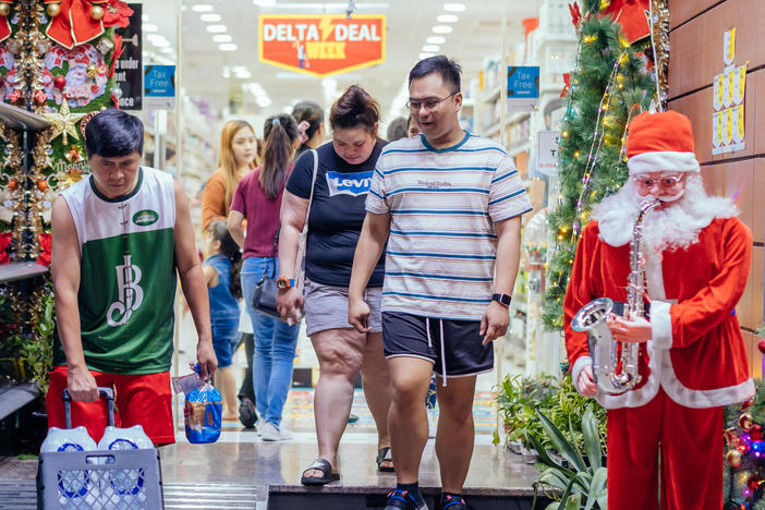 People leave a grocery store with Christmas decorations on Rigga Street in Dubai. Many Filipinos working in Dubai call this area home.