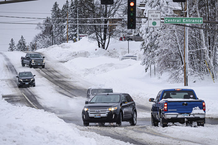 Cars slowly travel through an intersection after a second round of snow storm passed through northern Minnesota Thursday, Dec. 15, 2022, in Duluth, Minn.