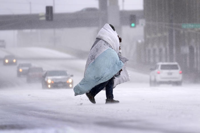 A person wrapped in a blanket crosses a snow-covered street Thursday in St. Louis.