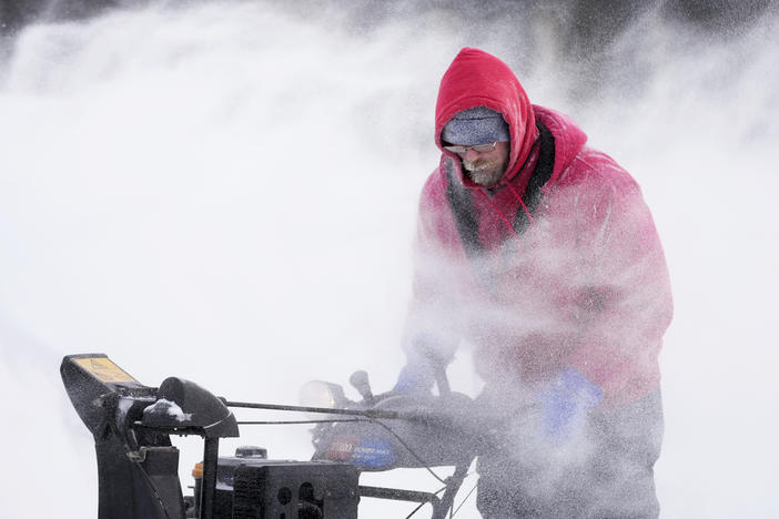 Mark Sorter clears snow on Friday from a downtown ice skating rink in Des Moines, Iowa.