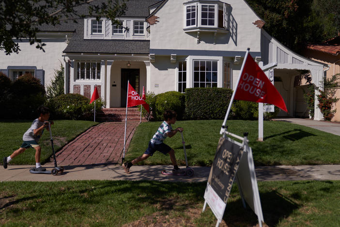 Children ride scooters past a house for sale in Los Angeles. Home sales have slowed as mortgage rates have climbed.