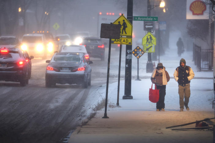 Pedestrians navigate a snow-covered sidewalk in Chicago, on Thursday. Severe winter weather has impacted tens of millions of people in the U.S.