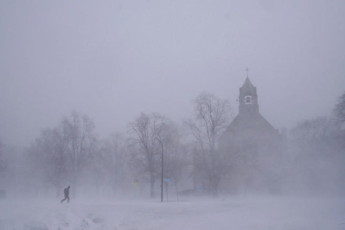 A lone pedestrian in snow shoes makes his way across Colonial Circle as St. John's Grace Episcopal Church rises above the blowing snow amid blizzard conditions in Buffalo, N.Y. on Saturday.