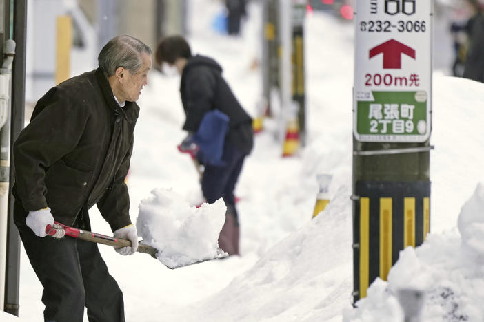 Residents shovel snow off a sidewalk in Kanazawa, Ishikawa prefecture, central Japan, on Dec. 24, 2022.