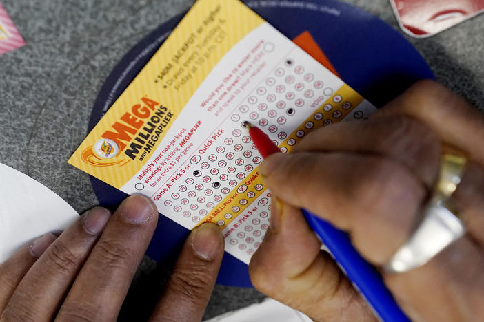 A customer is shown filling out a Mega Millions lottery ticket at a convenience store in Northbrook, Ill., on Jan. 6, 2021. The holiday shopping season, for Mega Millions lottery ticket buyers, at least, is ramping up as officials say the estimated jackpot for the drawing the night of Tuesday, Dec. 27, 2022, has surpassed half a billion dollars.